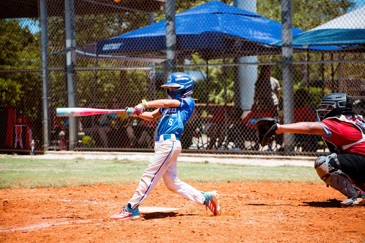 Baseball batter in blue uniform swinging at pitch during game with catcher in background.
