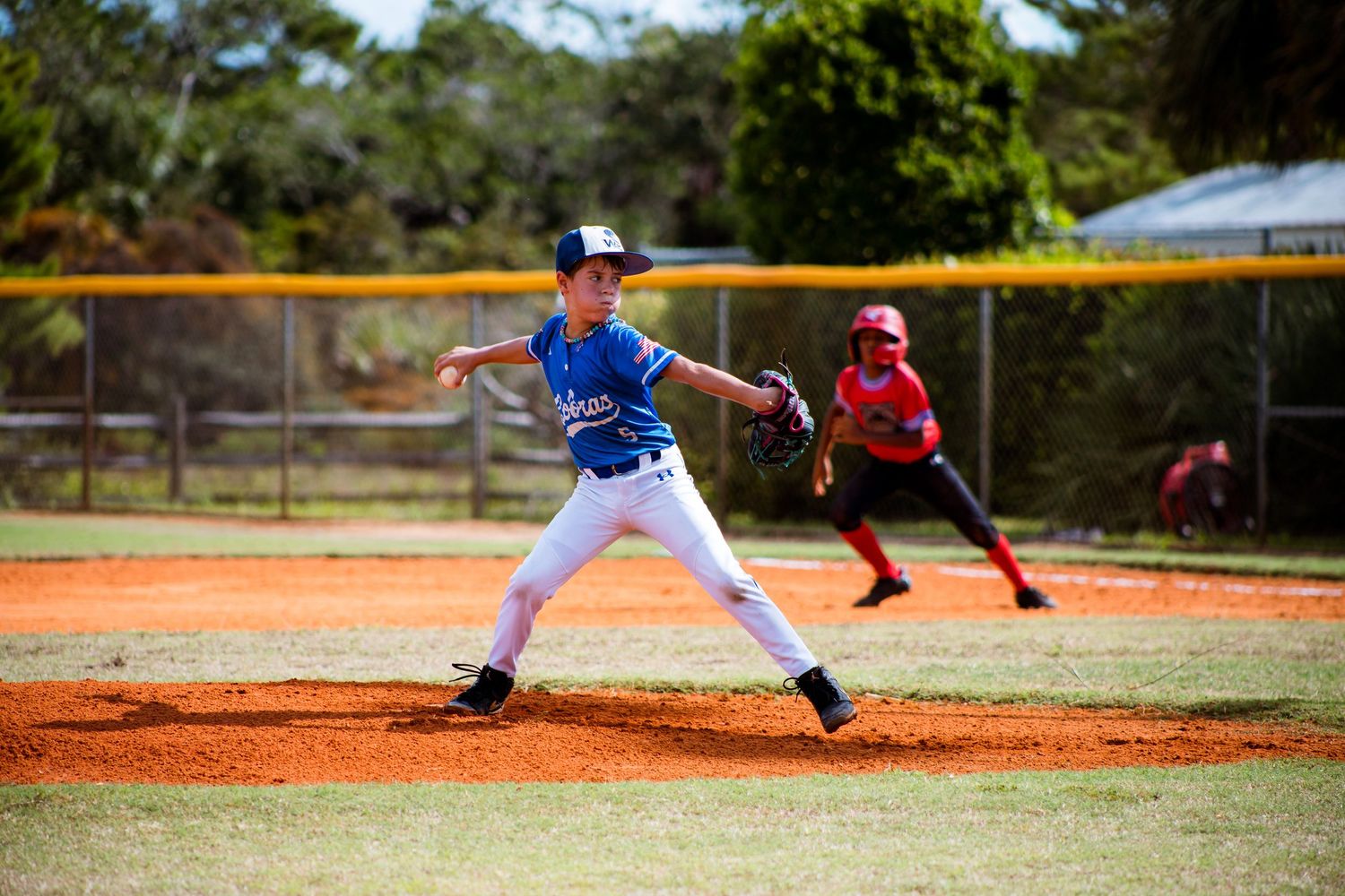 Baseball players on a sunny field with palm trees in the background during a game sequence.