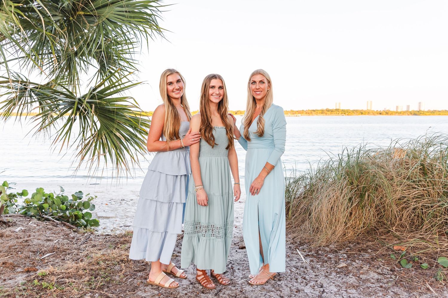 Beach family portrait session with everyone dressed in soft blue and mint tones.