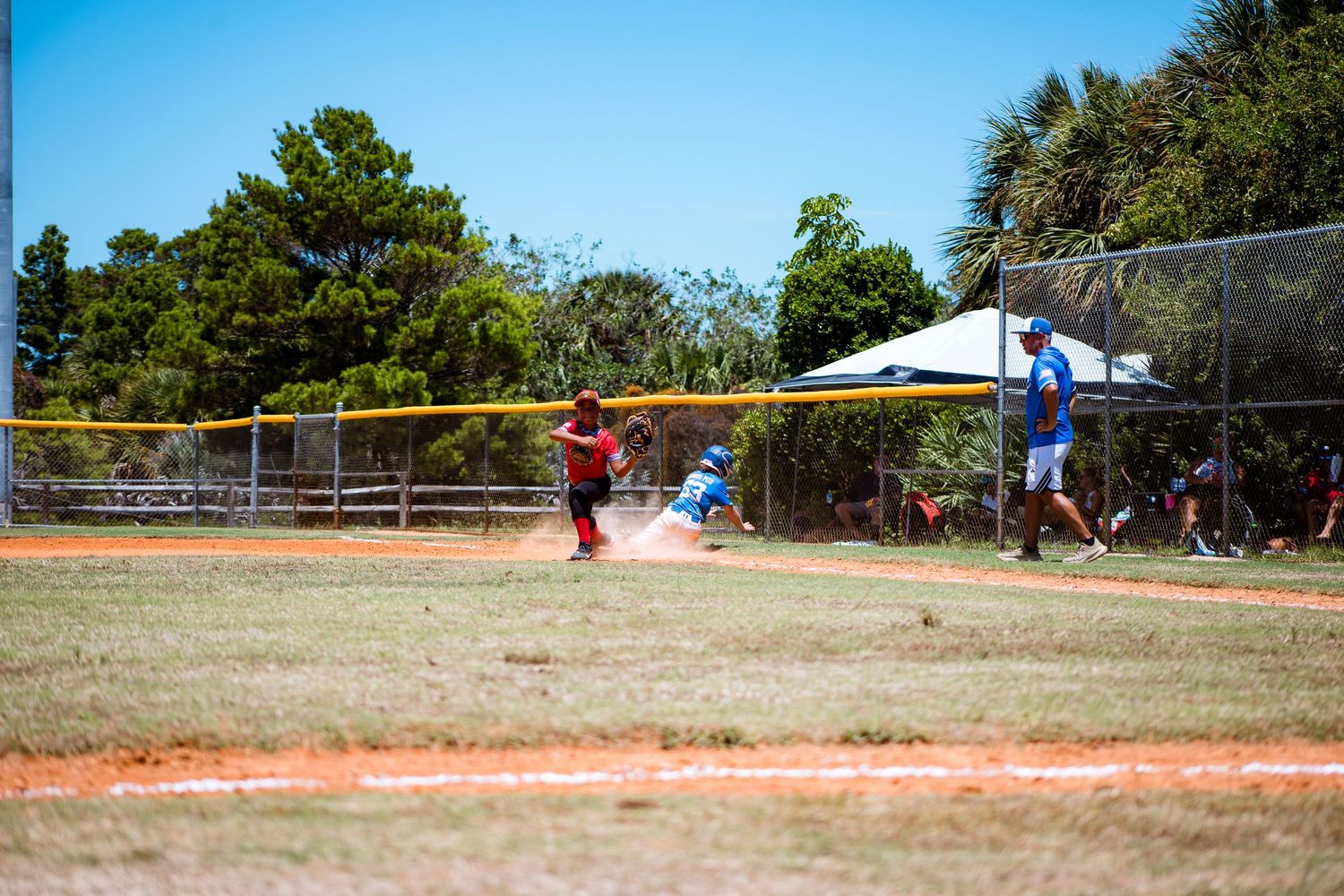 Baseball field under bright blue sky with players positioned for game action.