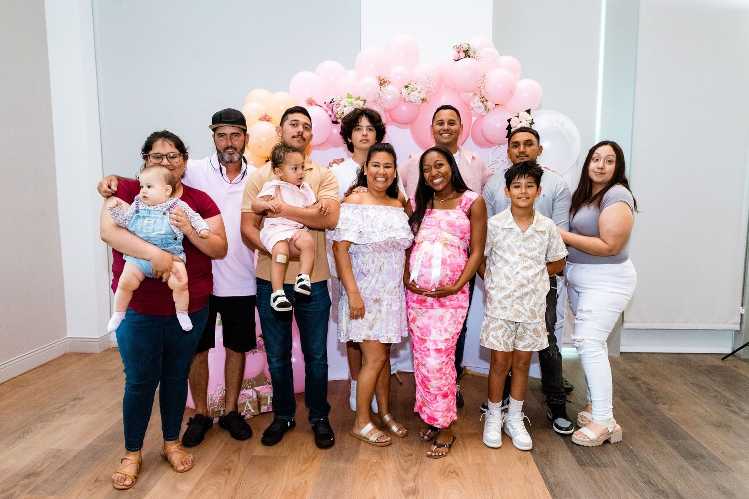 A large group gathered for a photo in front of a pink balloon display.