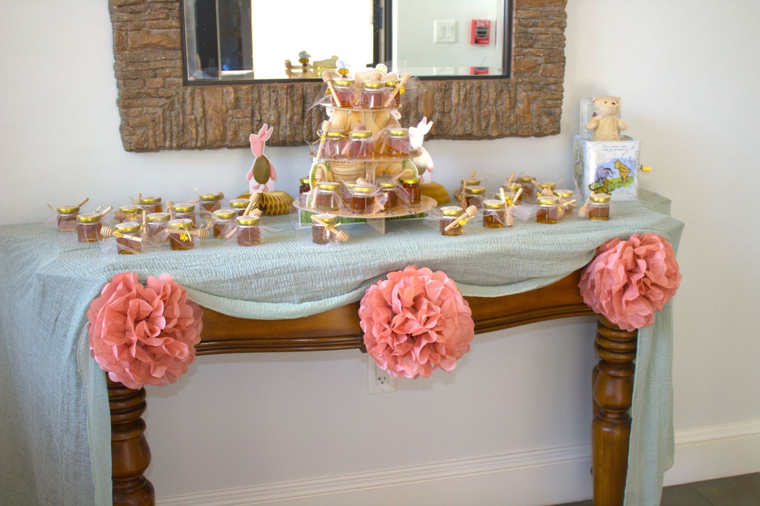 Dessert table with coral pink tissue flowers and golden accents displaying cupcakes and treats.