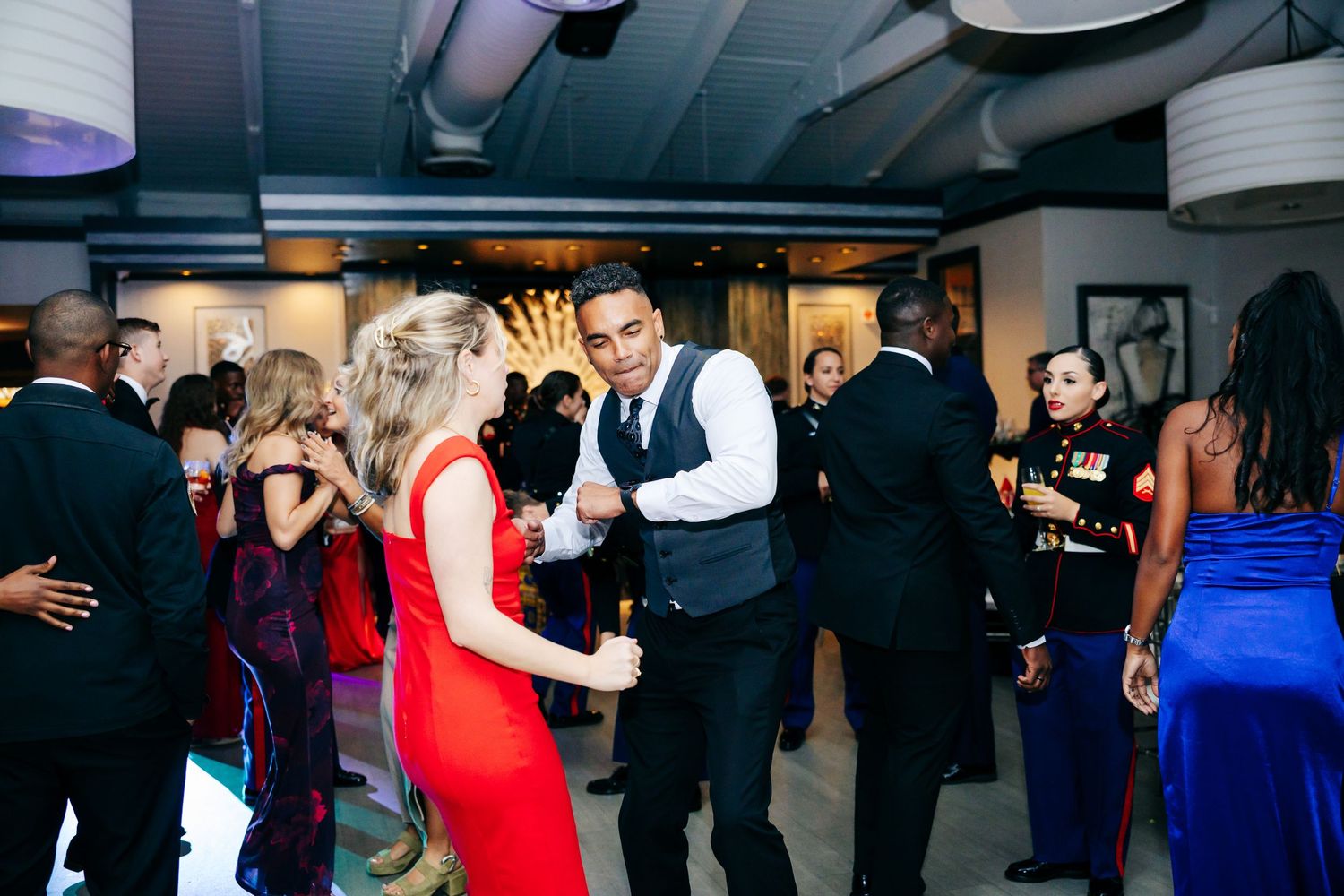Guests dancing and mingling at a formal military gala event.