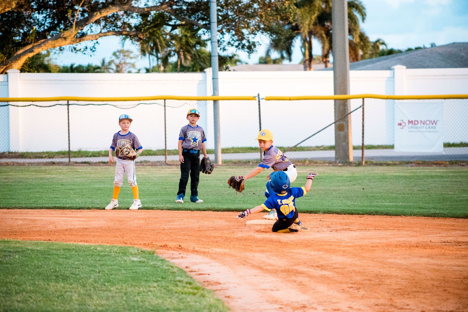 Youth baseball players and an umpire on a sunny baseball field during a baseball game.