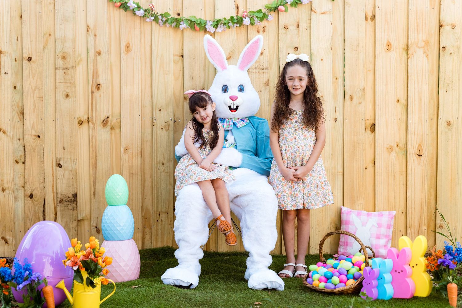 Easter photo setup with bunny costume character and spring decorations against wooden fence backdrop.