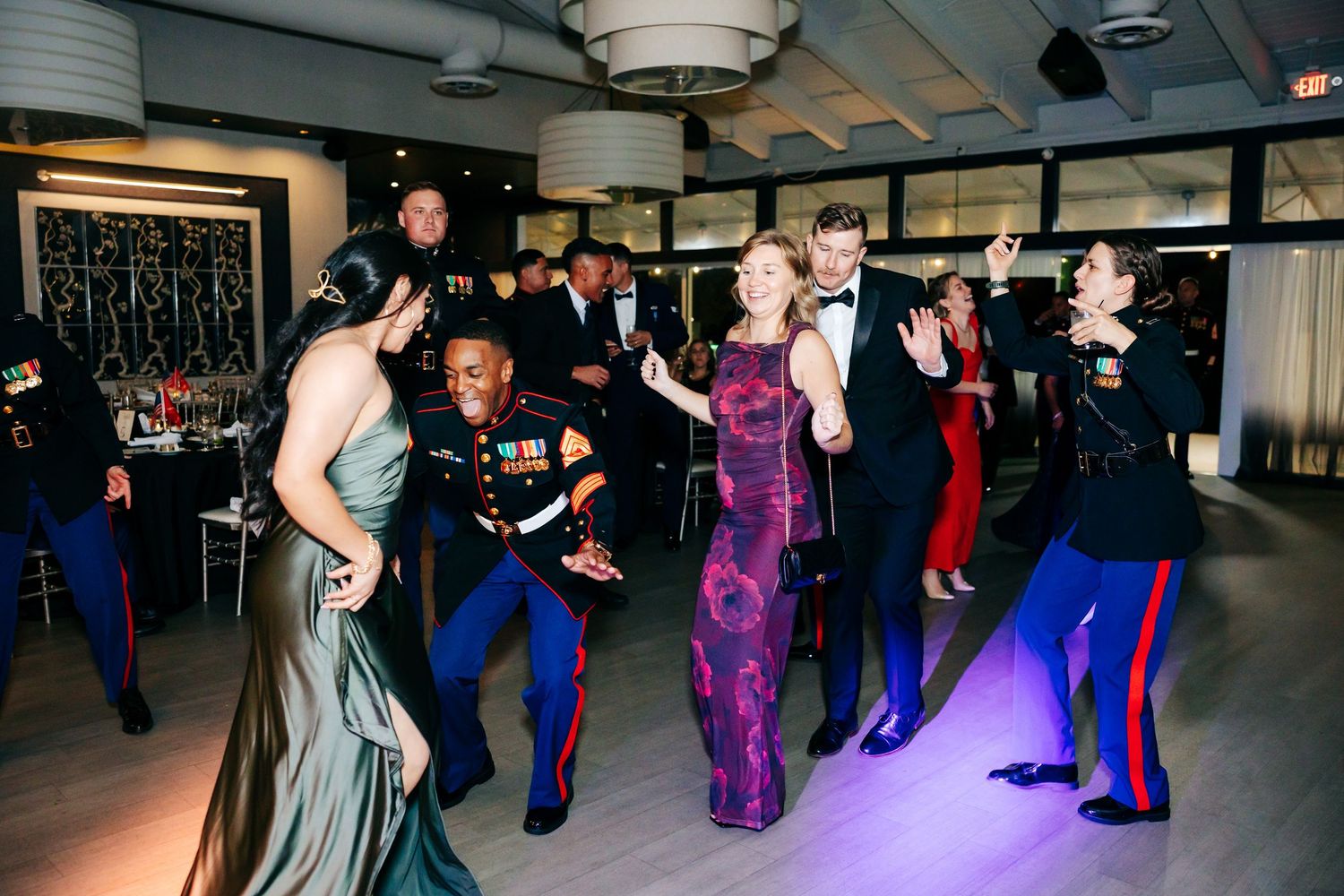 Couples dancing and socializing at a formal military ball in an elegant venue.