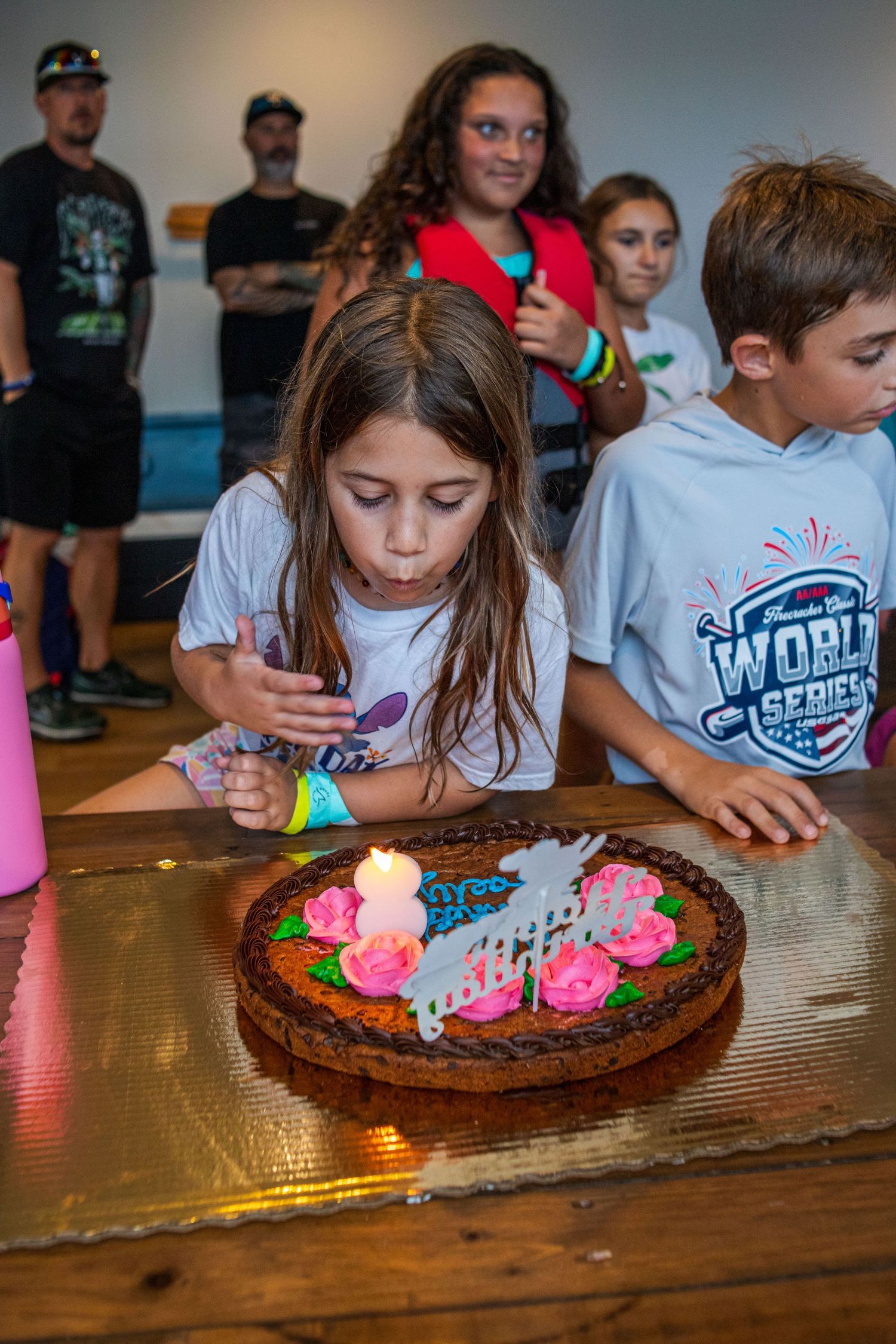Children gathered around a wooden table with decorated chocolate cakes at what appears to be a celebration.