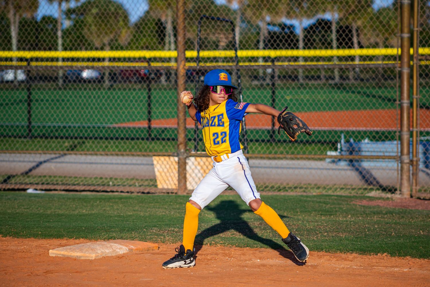 Baseball player stretching to catch ball during fielding practice on baseball diamond.