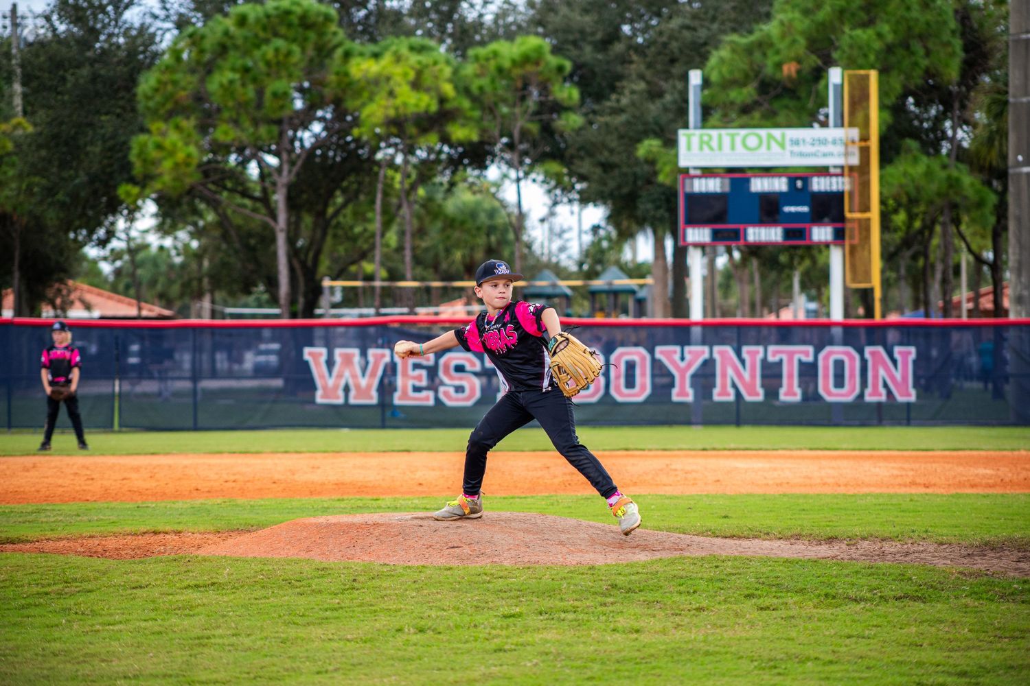 Wide view of baseball diamond showing players in pink uniforms during active gameplay.