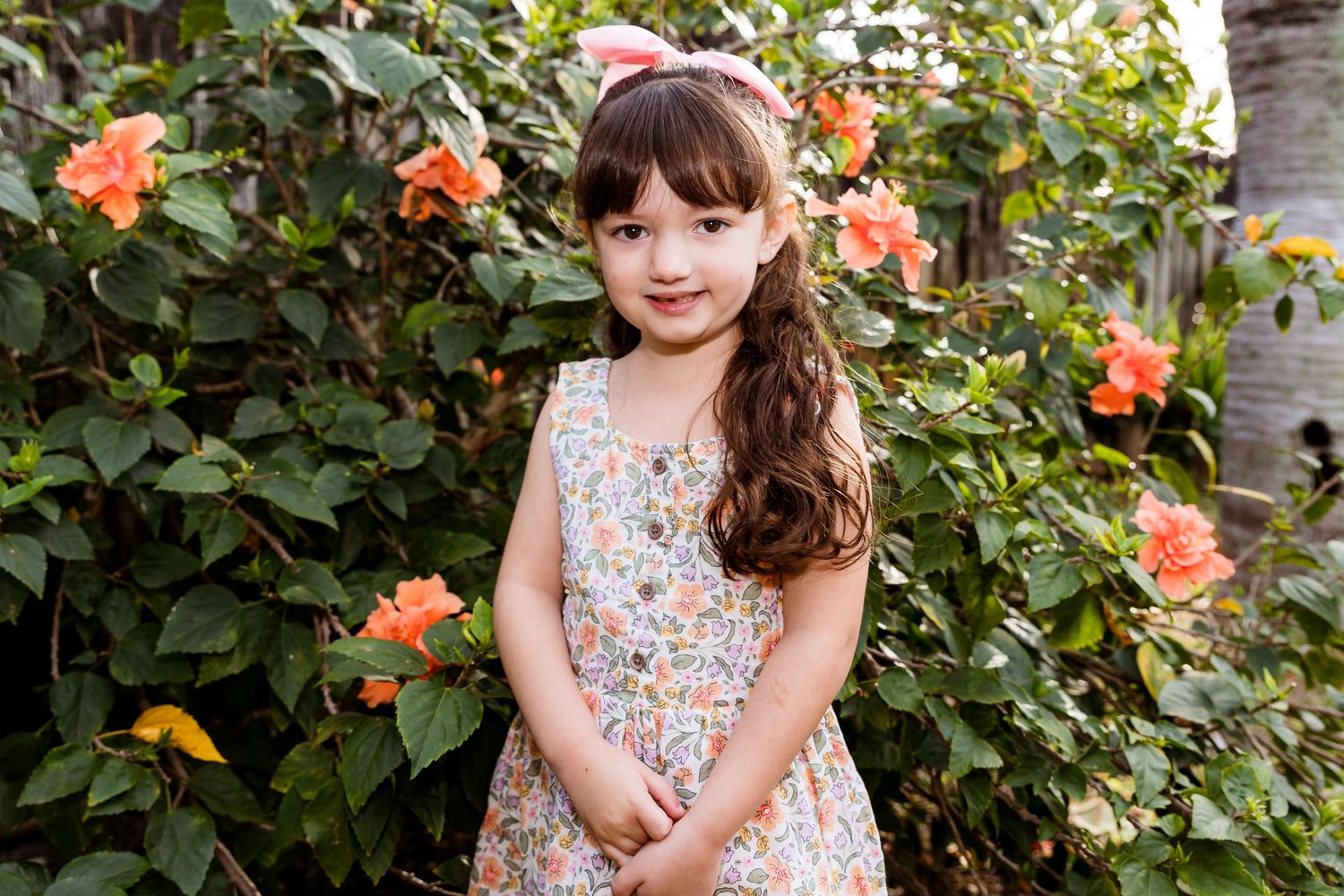 A spring portrait surrounded by blooming coral roses and green foliage.