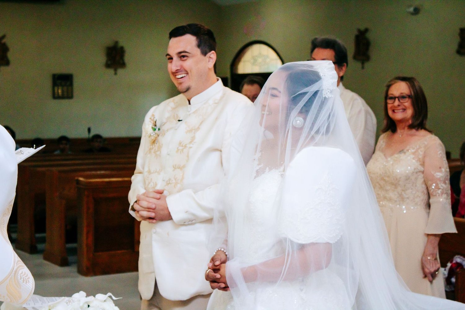 Wedding ceremony in progress inside a church with guests seated in wooden pews.
