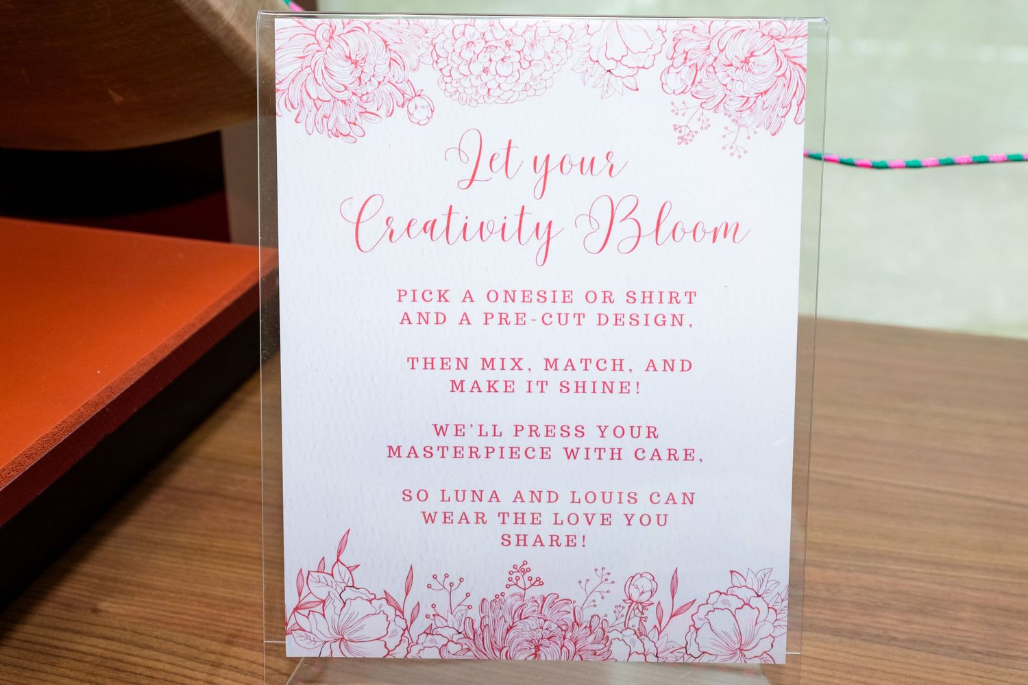 Pink floral themed event sign with 'Let your Creativity Bloom' text in elegant calligraphy.