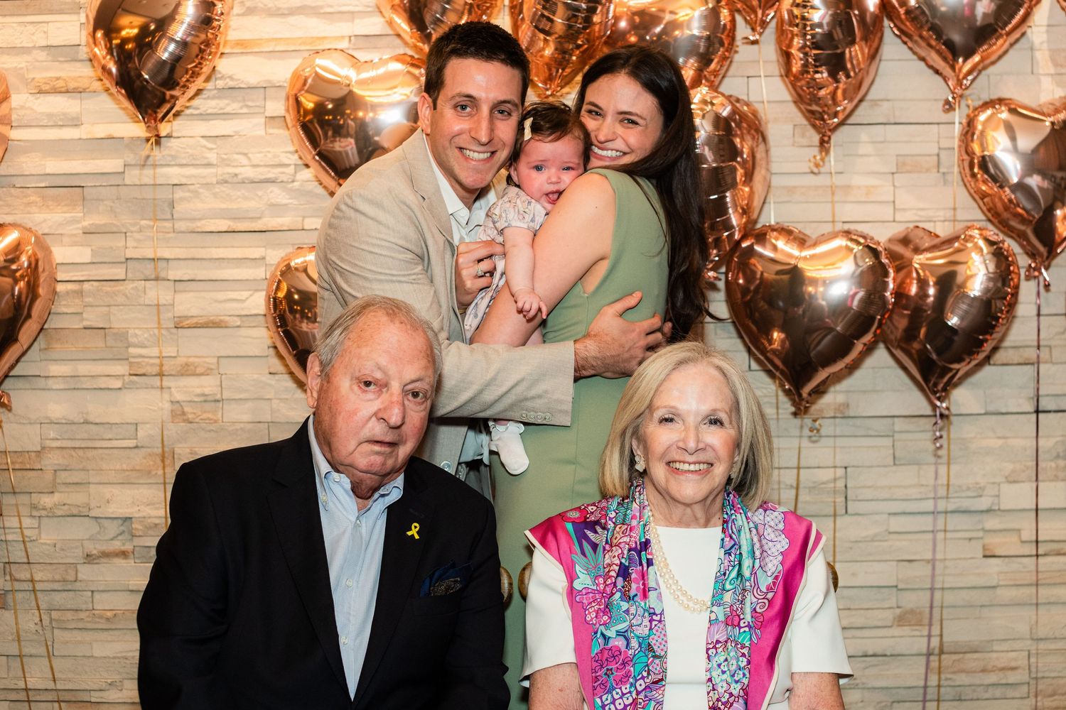 Multi-generational family gathering with rose gold heart balloon decorations.