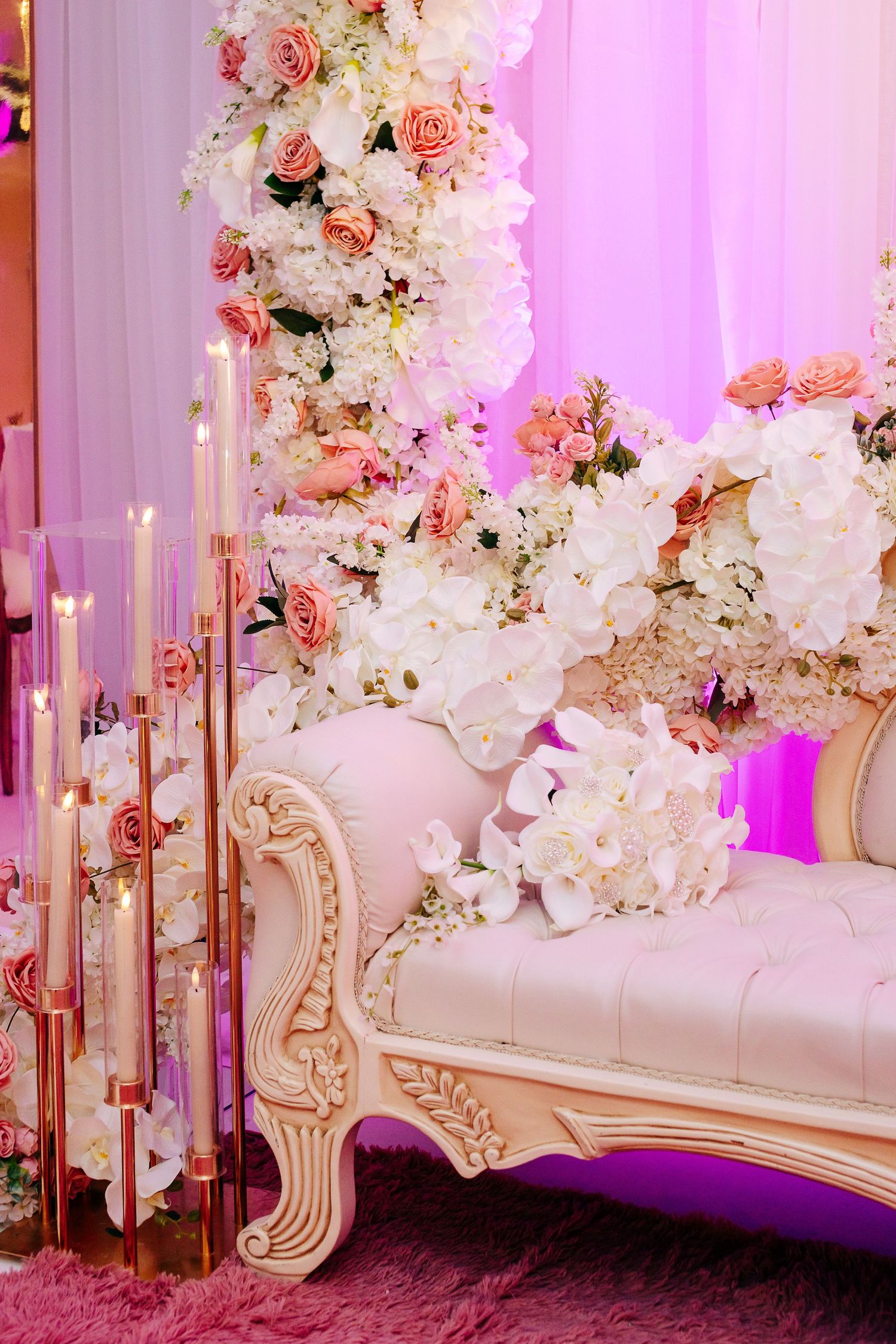 Elegant white and pink floral wedding stage decoration with ornate gold furniture and candlesticks.