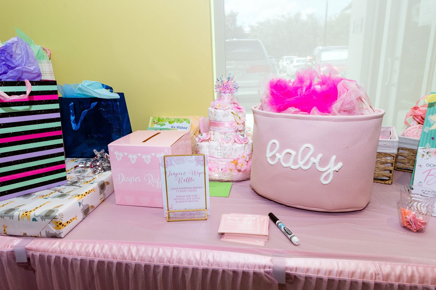 Baby shower dessert table decorated in pink with white displays and sweet treats.