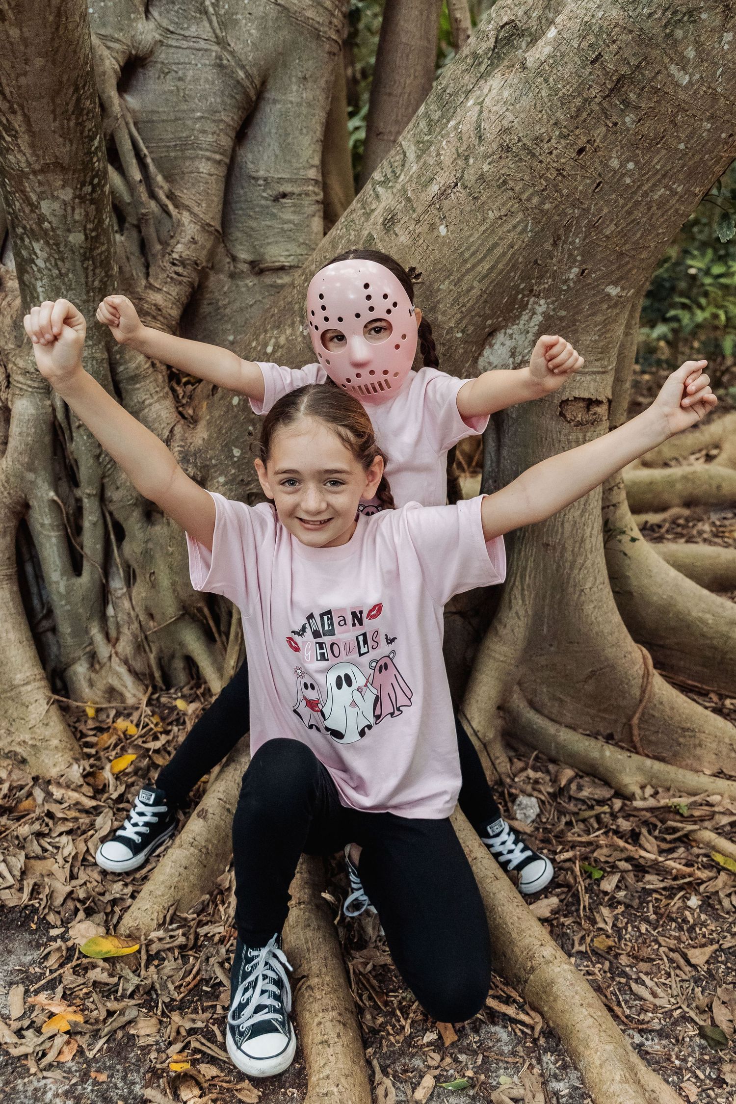 A series of playful poses next to a large tree trunk showing someone in a pink t-shirt and black pants.