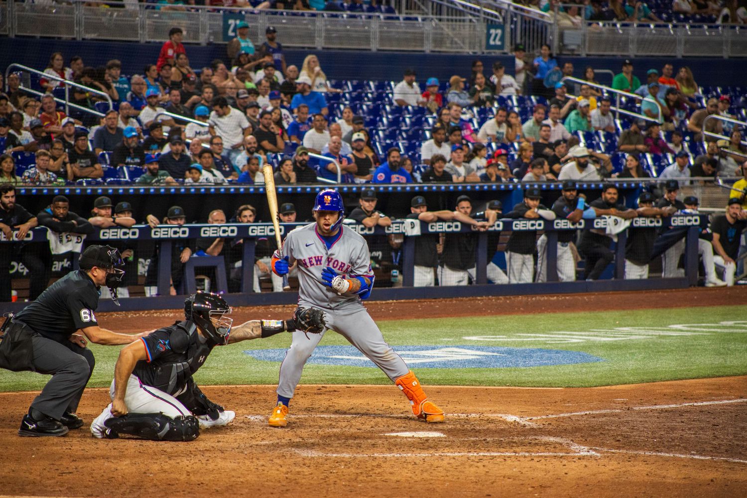 Baseball batter in road grey uniform takes stance at plate during nighttime game.