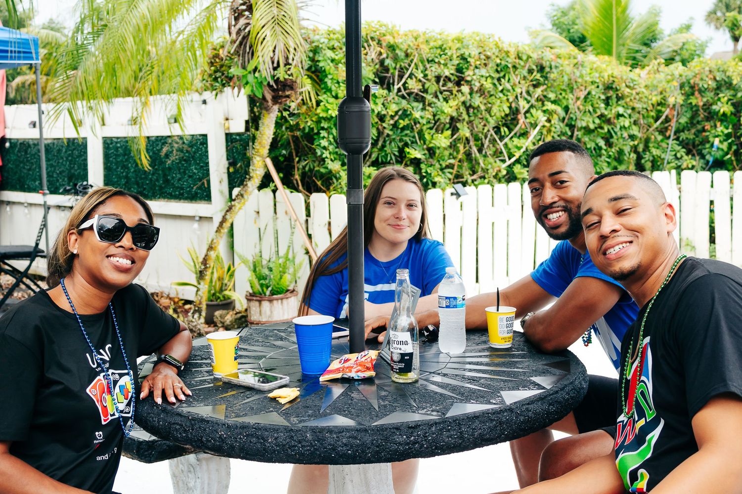 Friends enjoying drinks and conversation at an outdoor table during a party.
