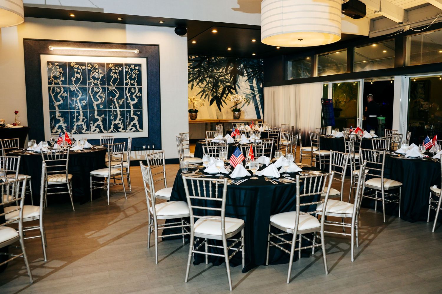 Elegant banquet hall setup with white chiavari chairs and formal table settings for military event.