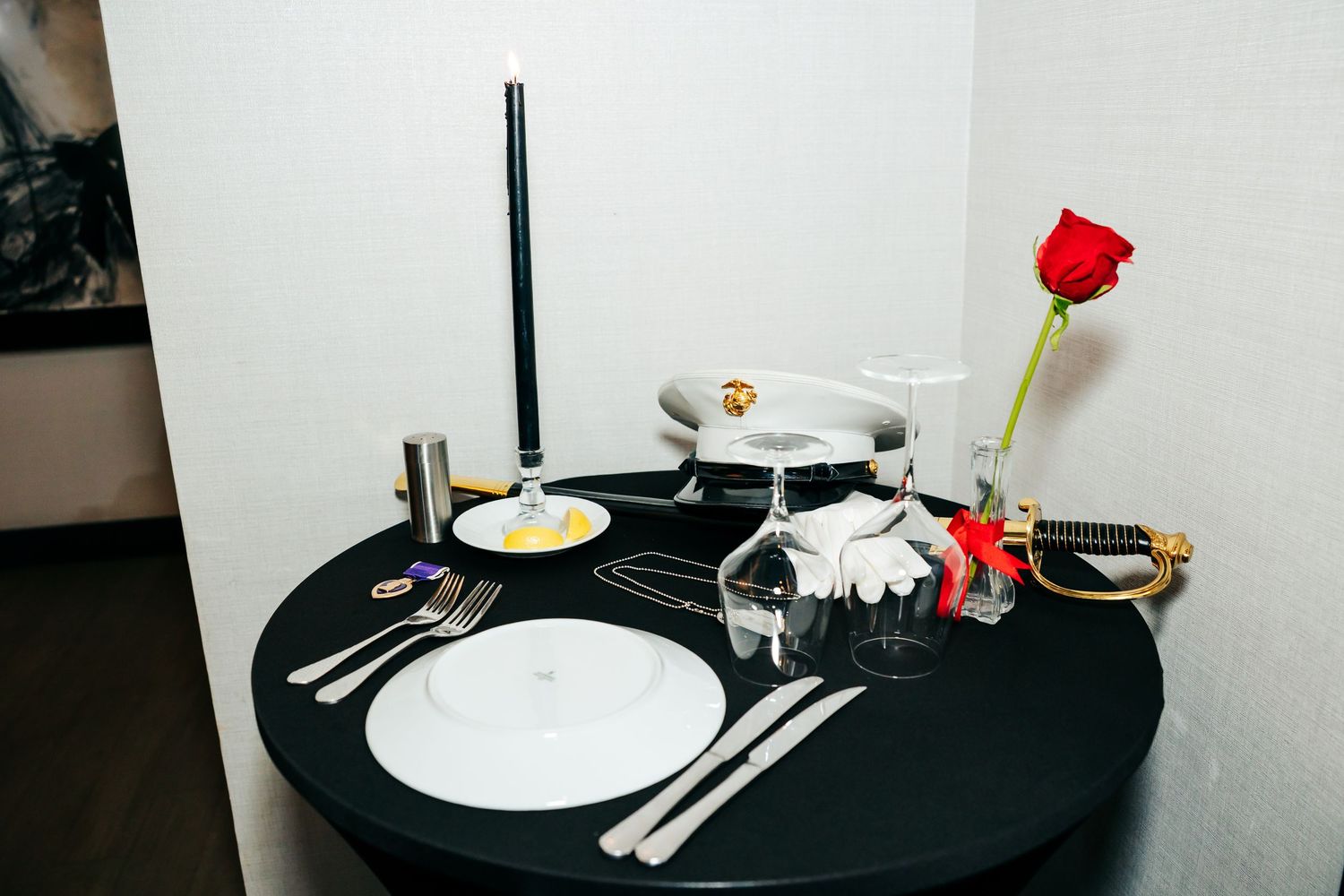 Table setting with white plates and black tablecloth at a formal military dinner event.