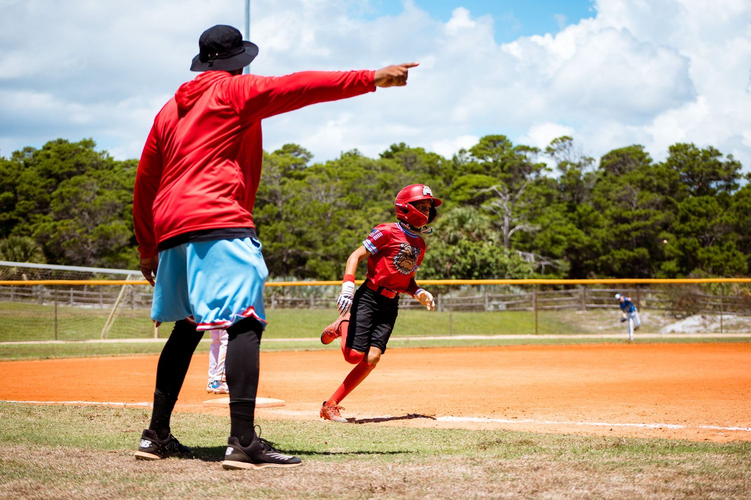 Baseball coaches in red uniforms directing players on the field during a game.