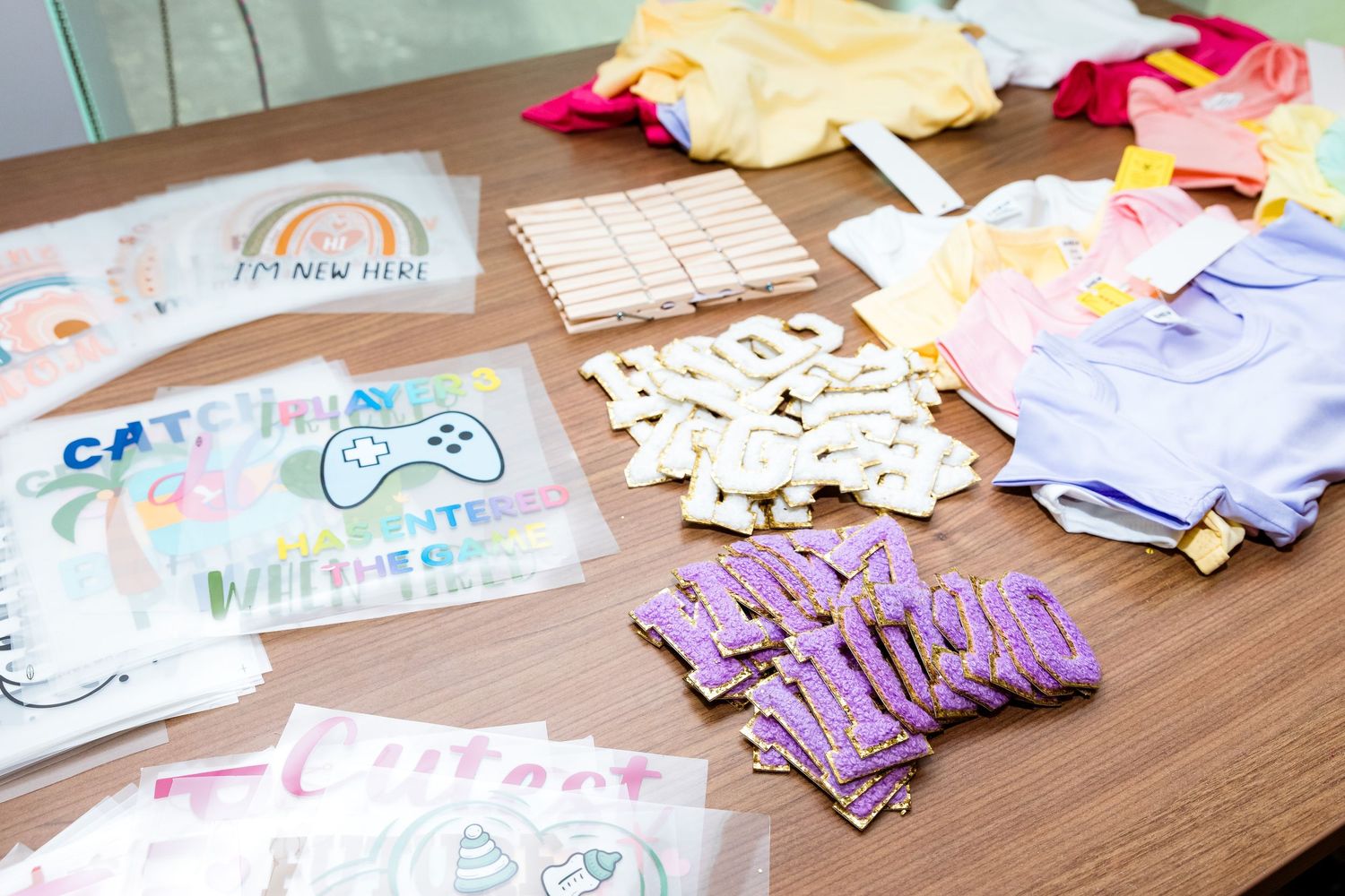 Crafting materials and decorative elements spread across a wooden table including cards and cut-out letters.