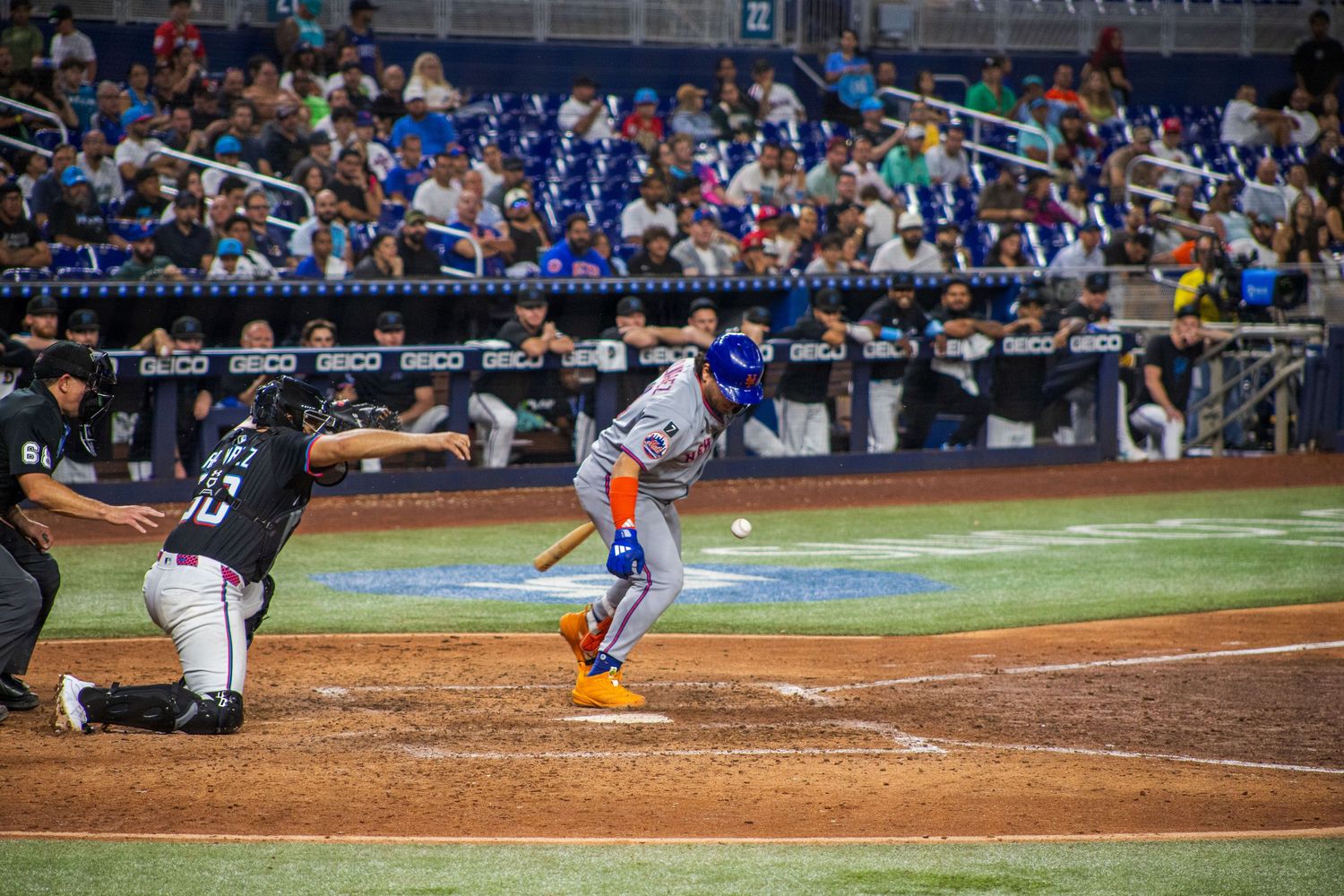 Baseball player at bat faces pitcher during night game with crowd visible in background.