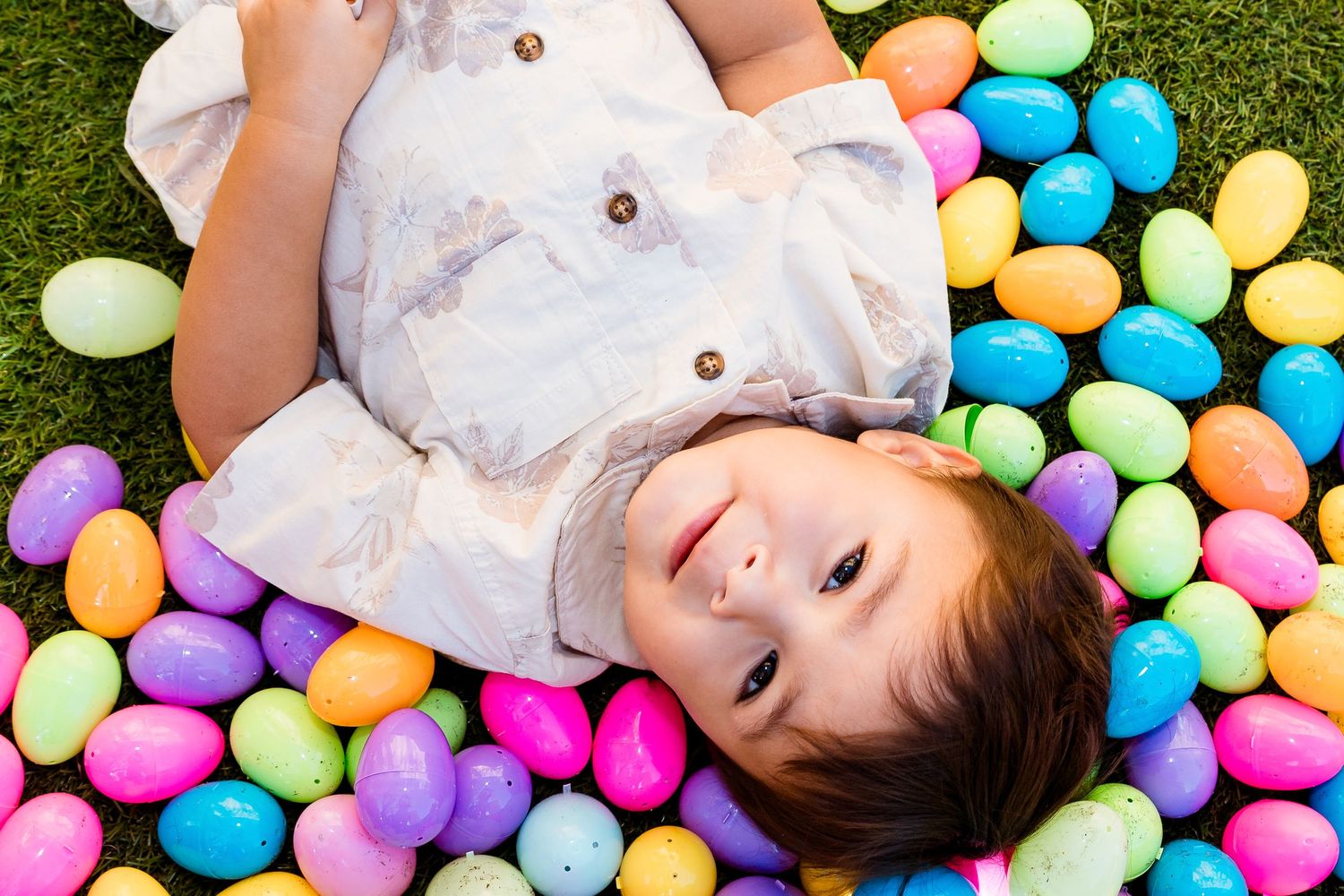 Colorful plastic Easter eggs scattered on green grass create a festive spring holiday scene.