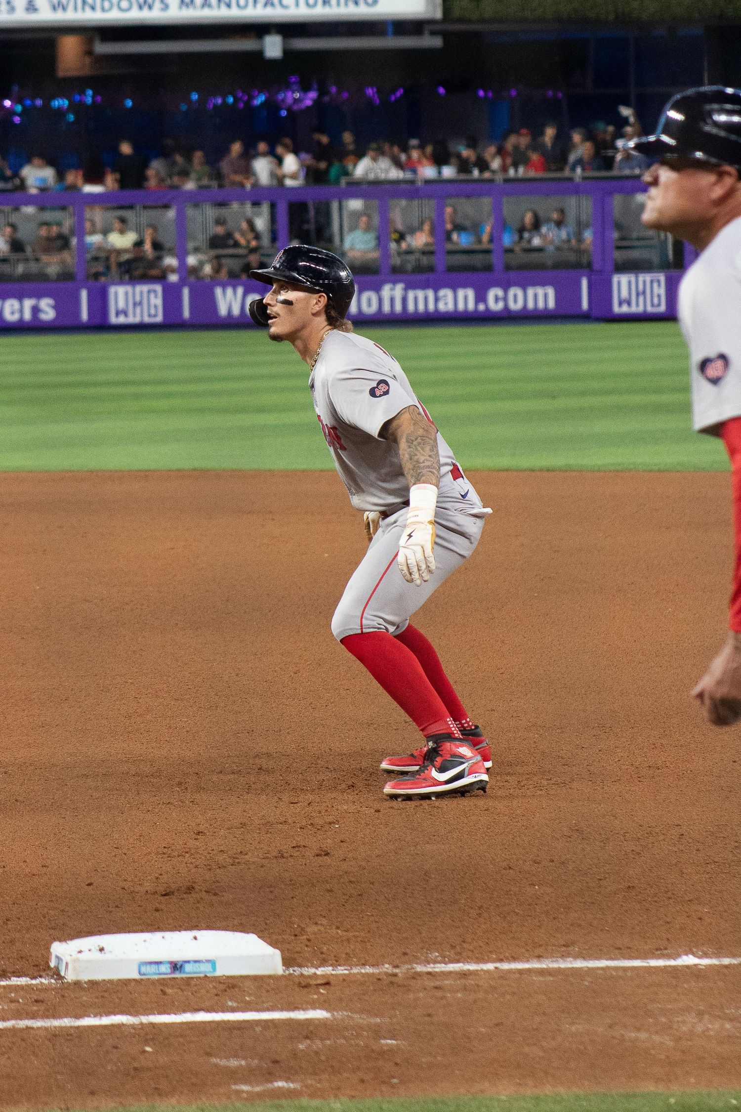 Baseball player in white uniform takes lead off first base during game.