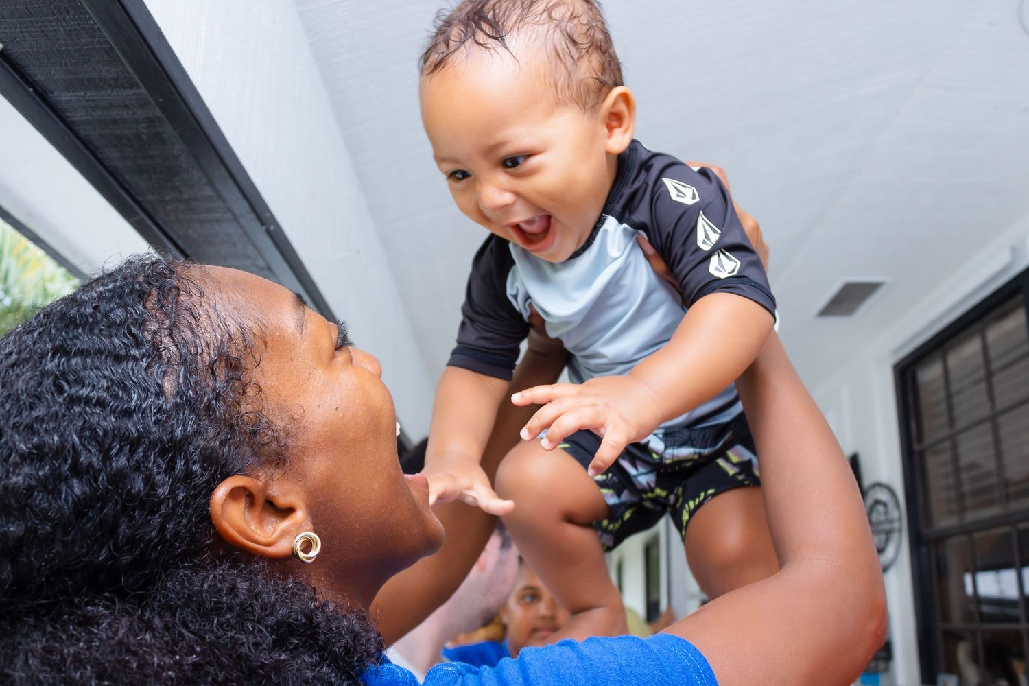 Parent and baby sharing a joyful moment together indoors.
