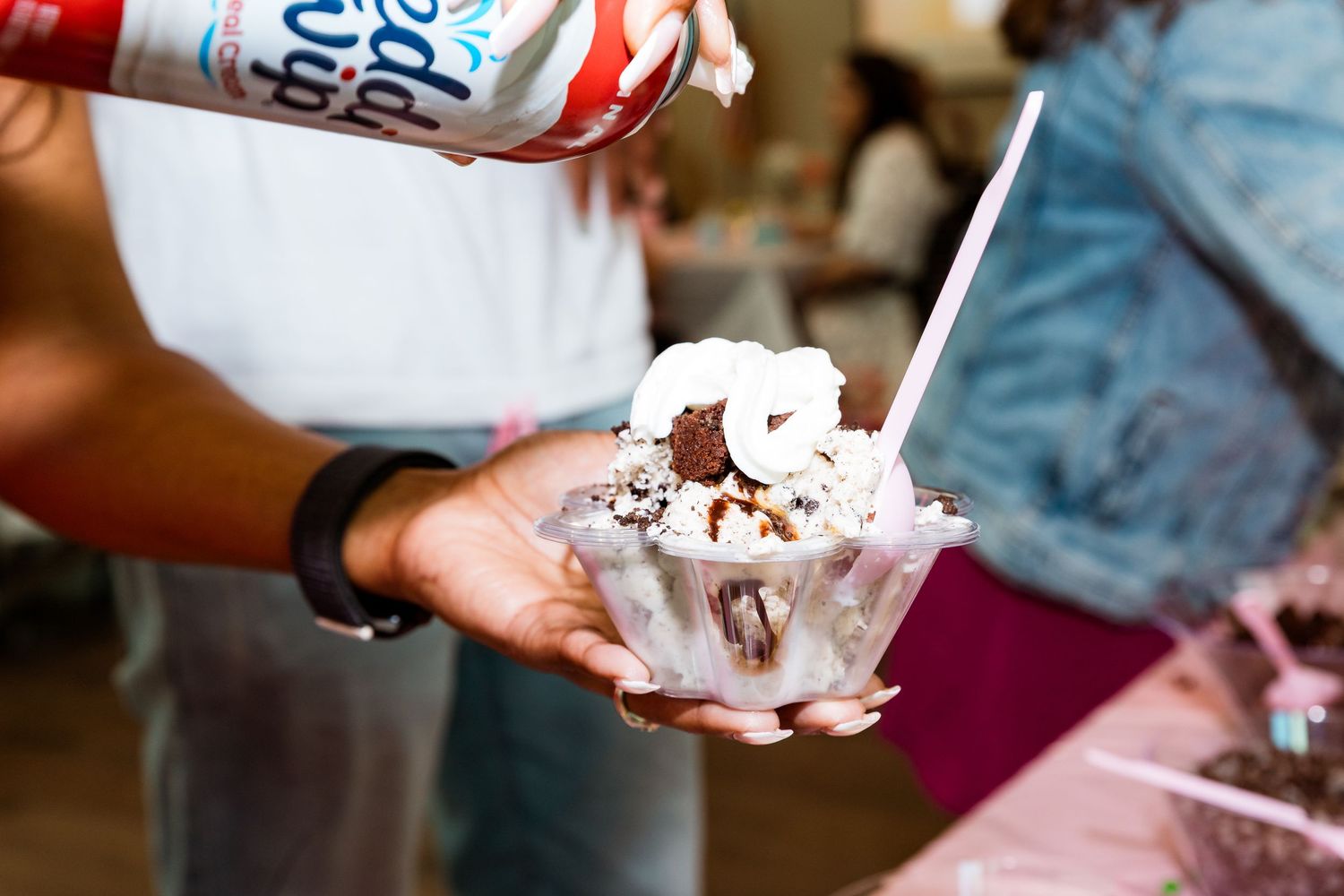 Close-up of whipped cream being sprayed onto a dessert with chocolate sprinkles.
