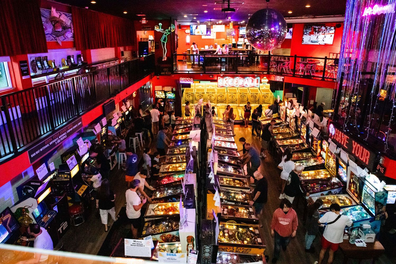 An image of a crowded, vibrant arcade with neon lights, video game machines, and people enjoying the atmosphere.