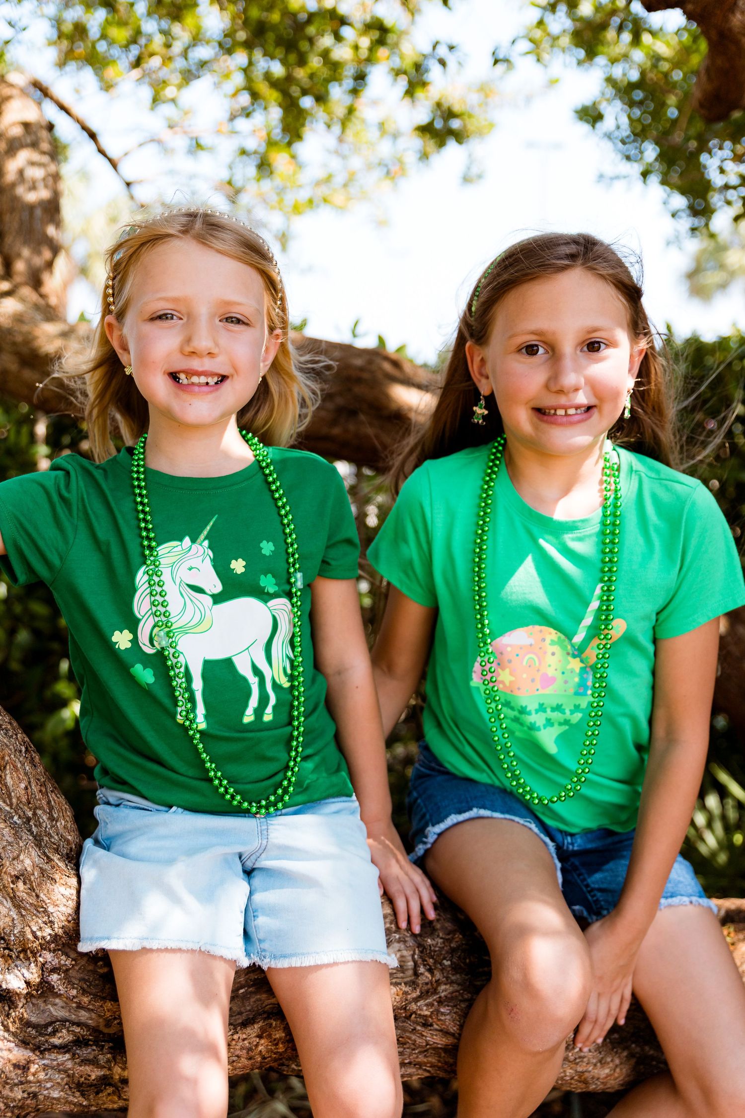 Two children wearing festive green shirts with unicorn and rainbow designs.