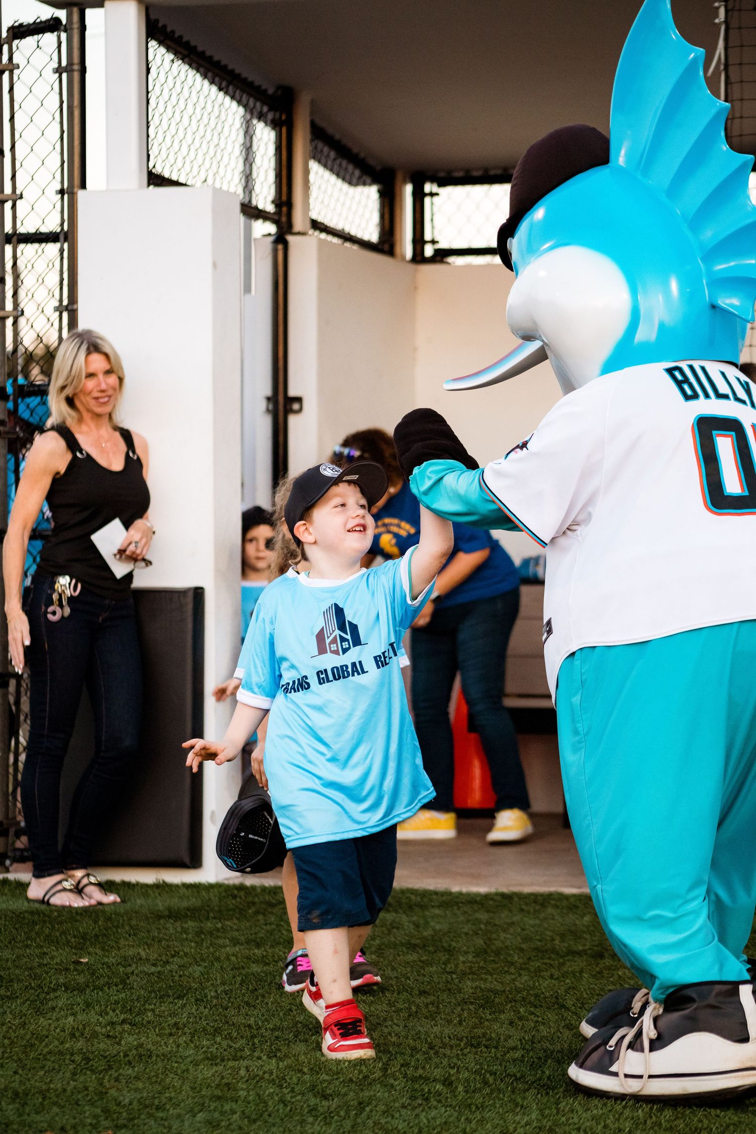 Marlins mascot Billy greets young fan in team facility walkway.