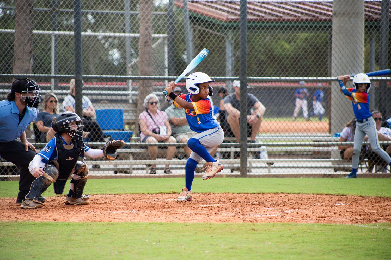 Baseball batter in blue uniform mid-swing at home plate during competitive game.