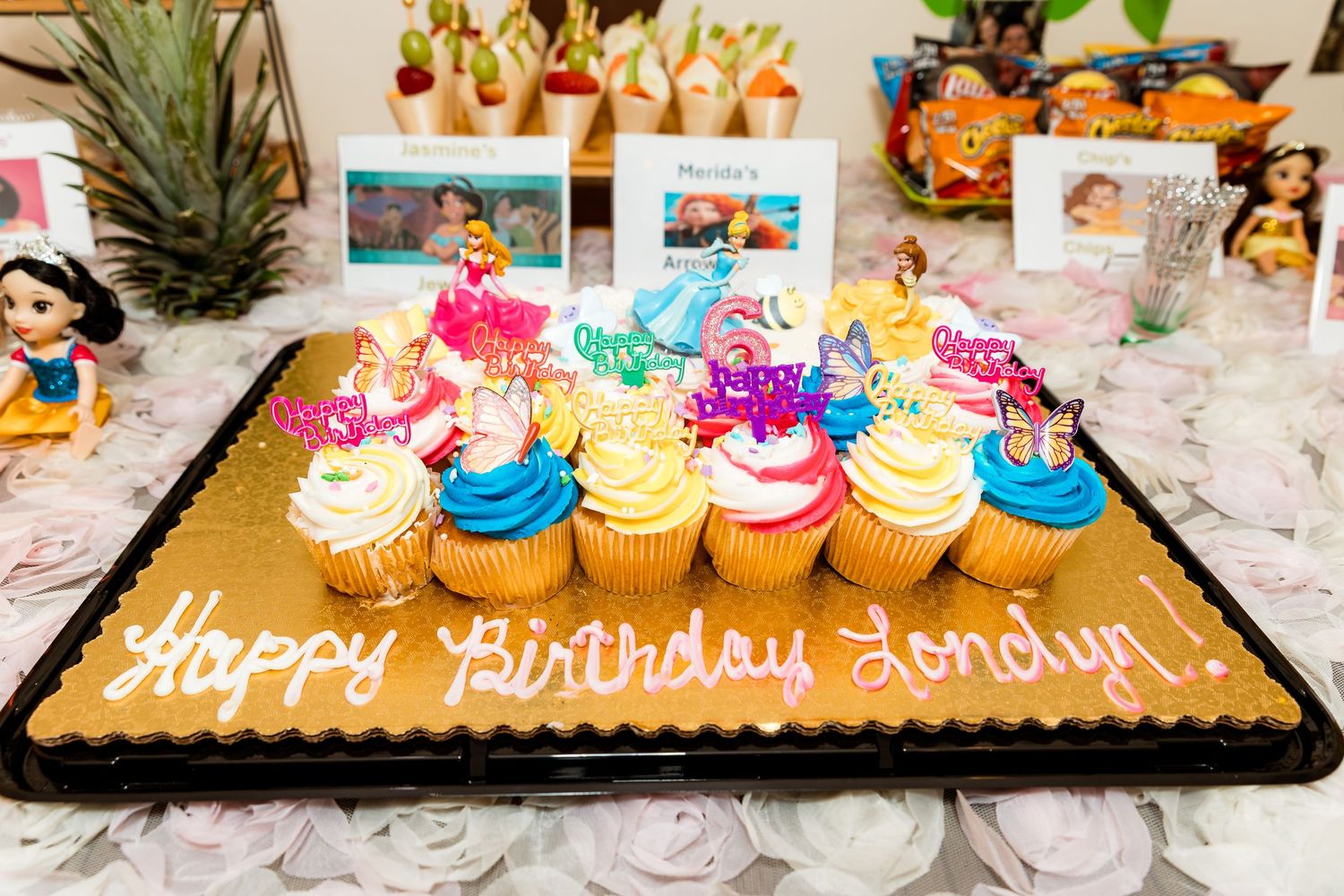 Colorful cupcakes and birthday cake display on marble table with succulents.