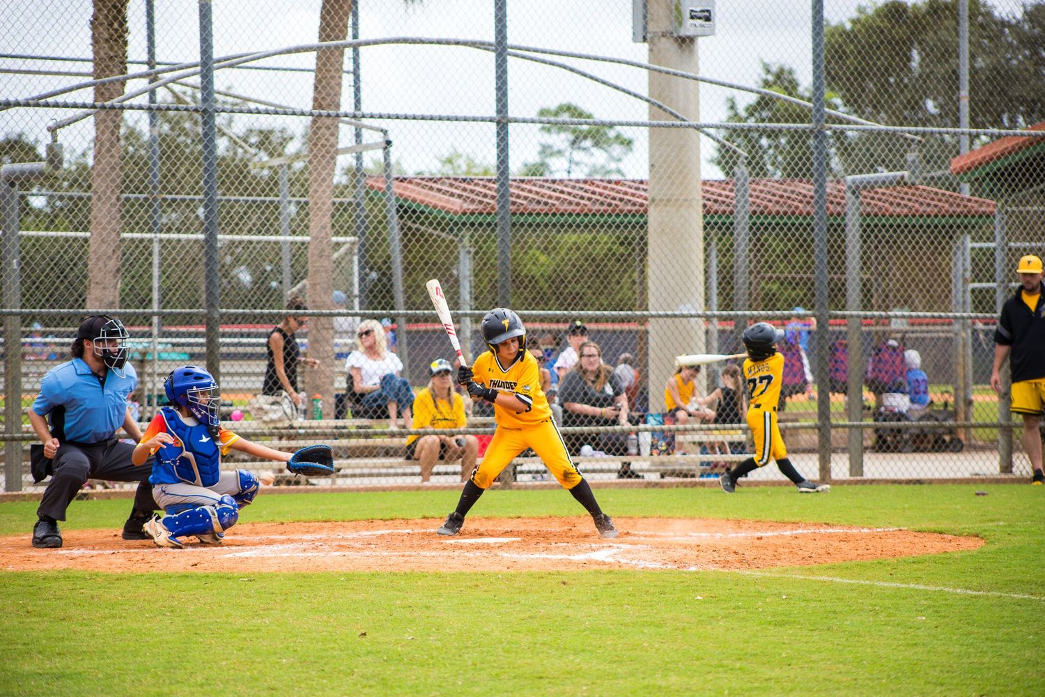 Baseball batter in yellow uniform takes powerful swing during competitive game.