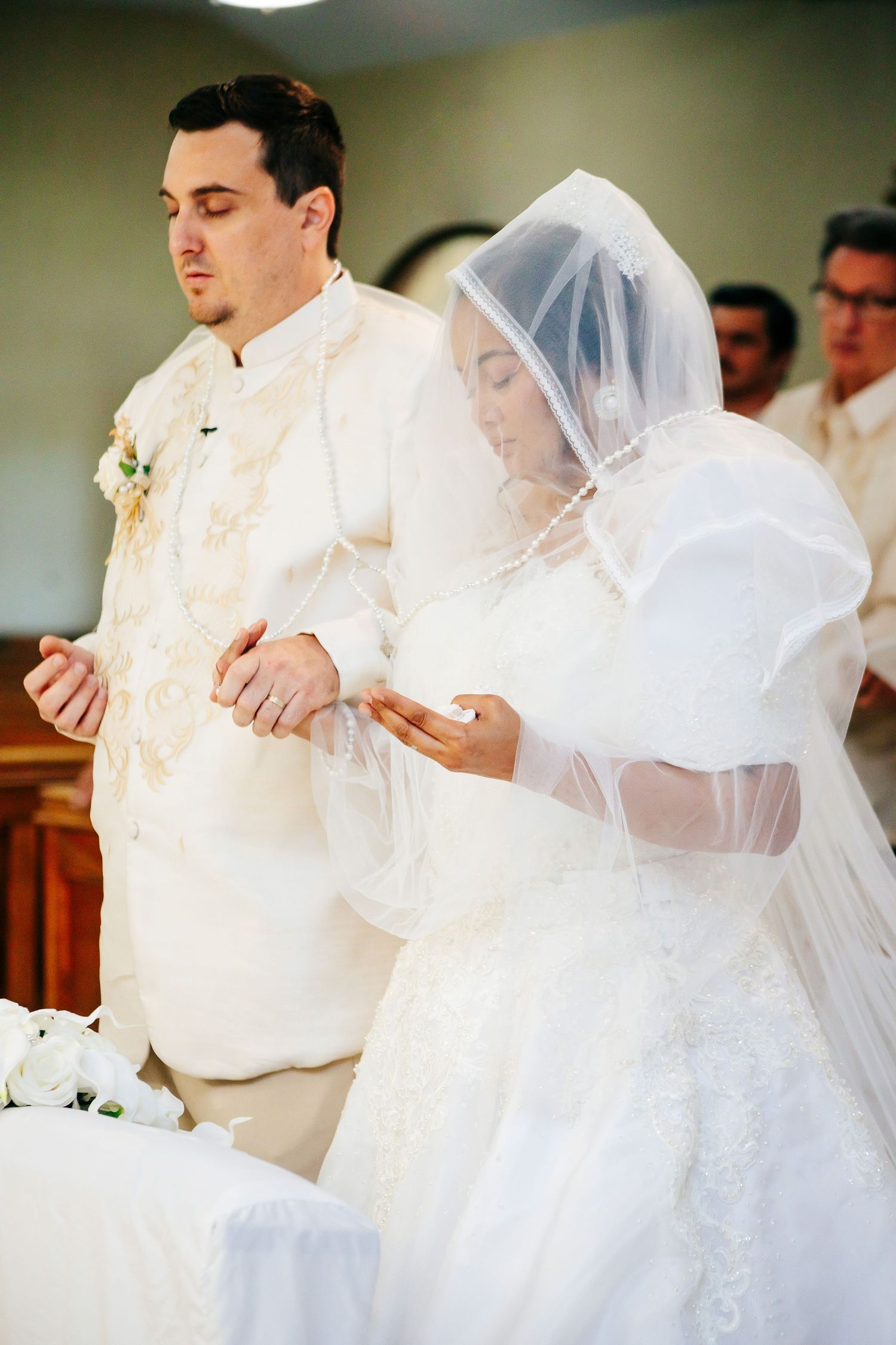 Bride and groom pray together during traditional Catholic wedding ceremony.