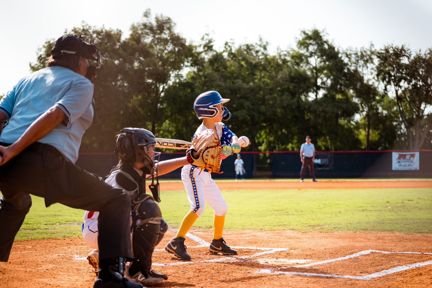 A softball player in a blue uniform rounds home plate during an outdoor game on a sunny day.