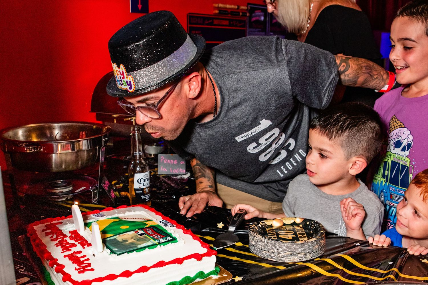 A man and a young child cutting a birthday cake together in a bar.