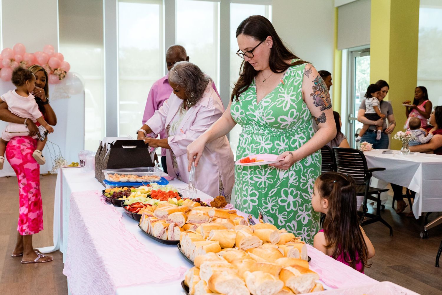 People organizing and preparing customized baby clothes and accessories at a crafting event.