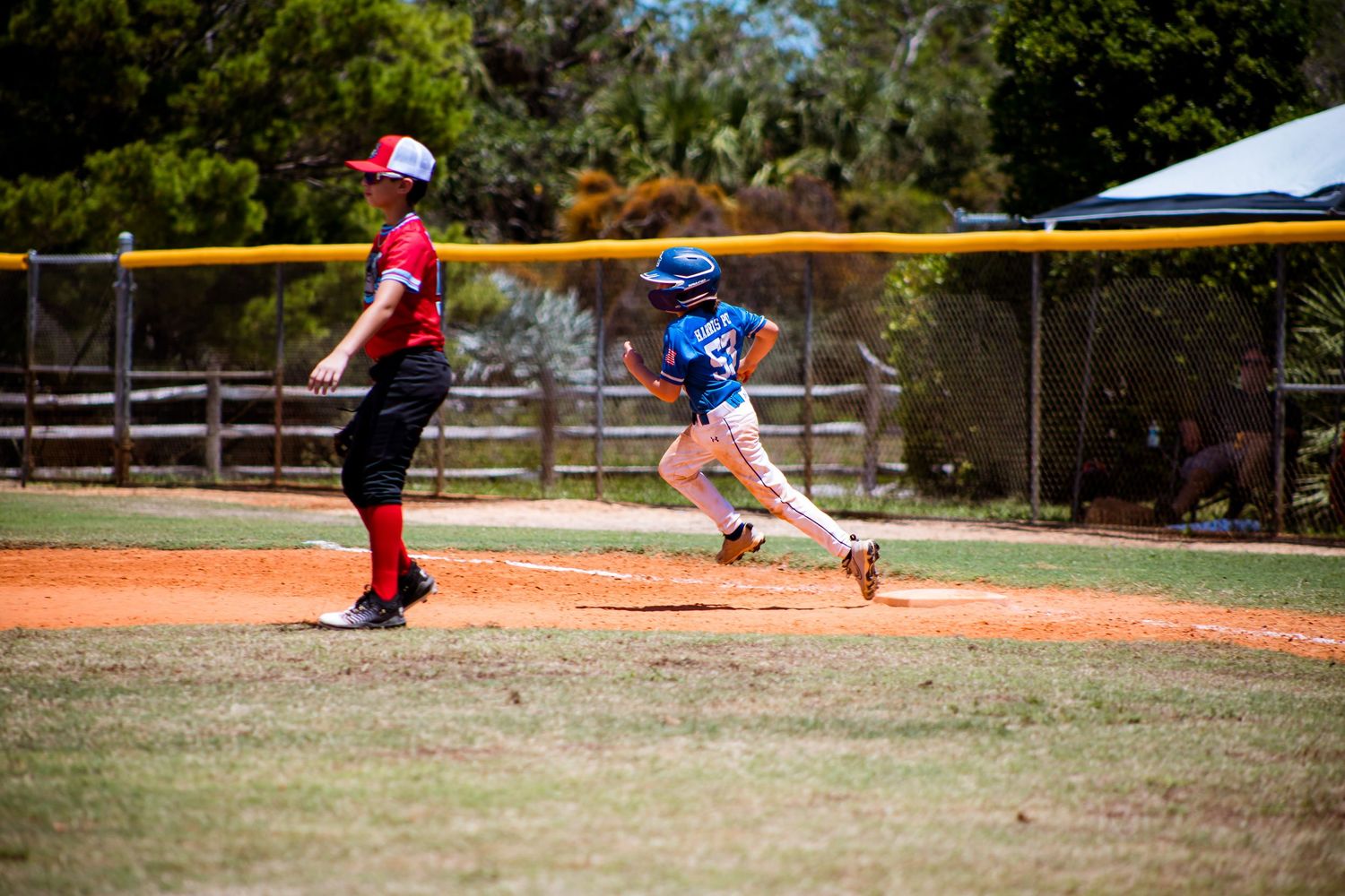 Baseball players from opposing teams in action during a youth league game.