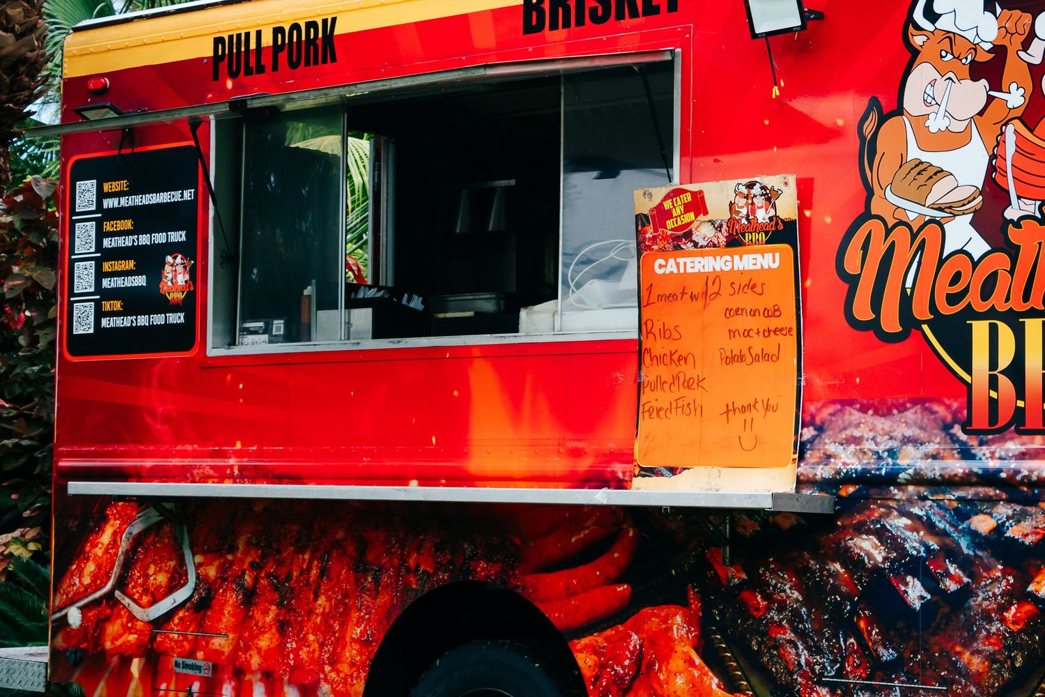 Colorful food truck vendor setup with bright red signage at night.