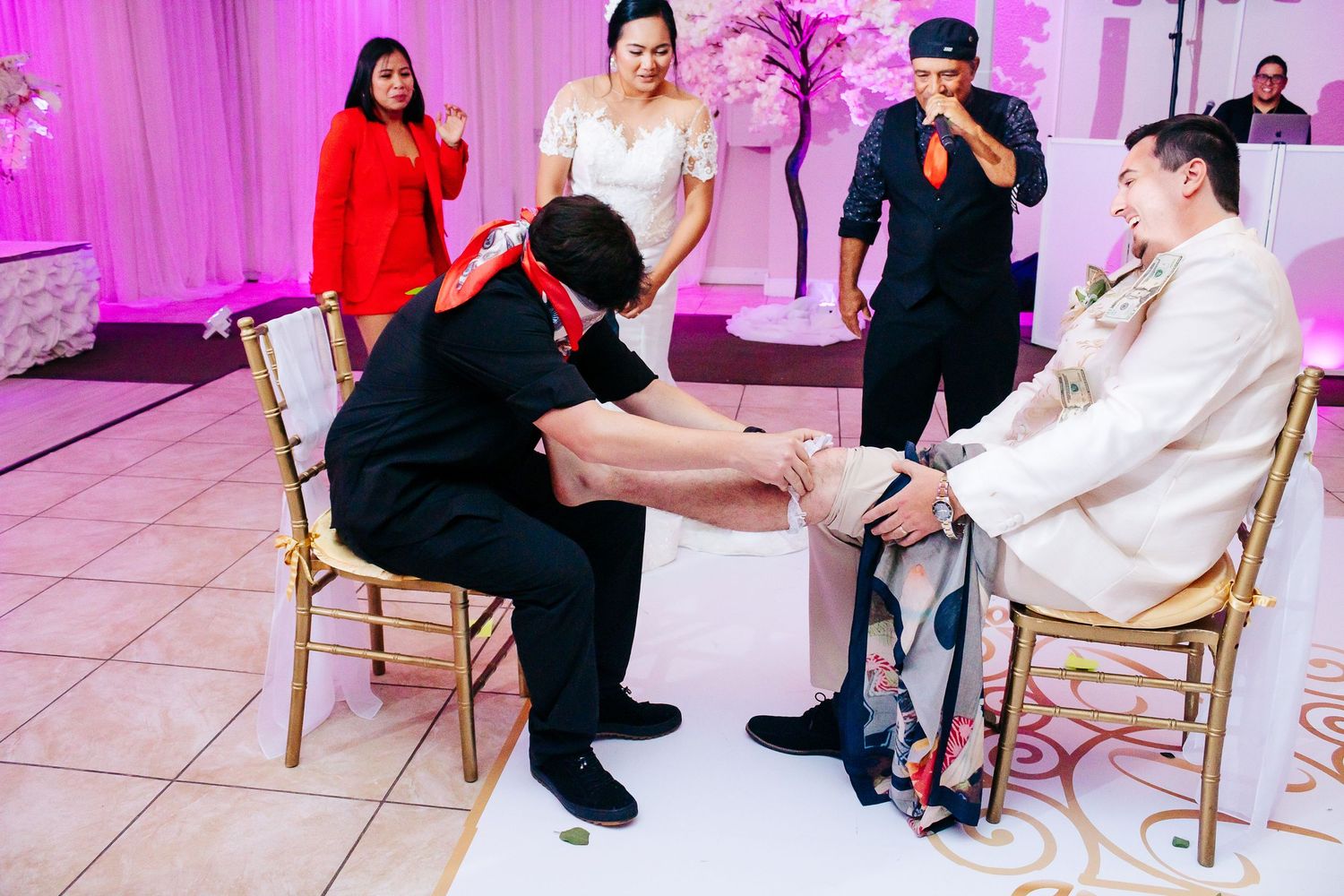 Wedding reception guests participating in a traditional shoe game activity with pink lighting.