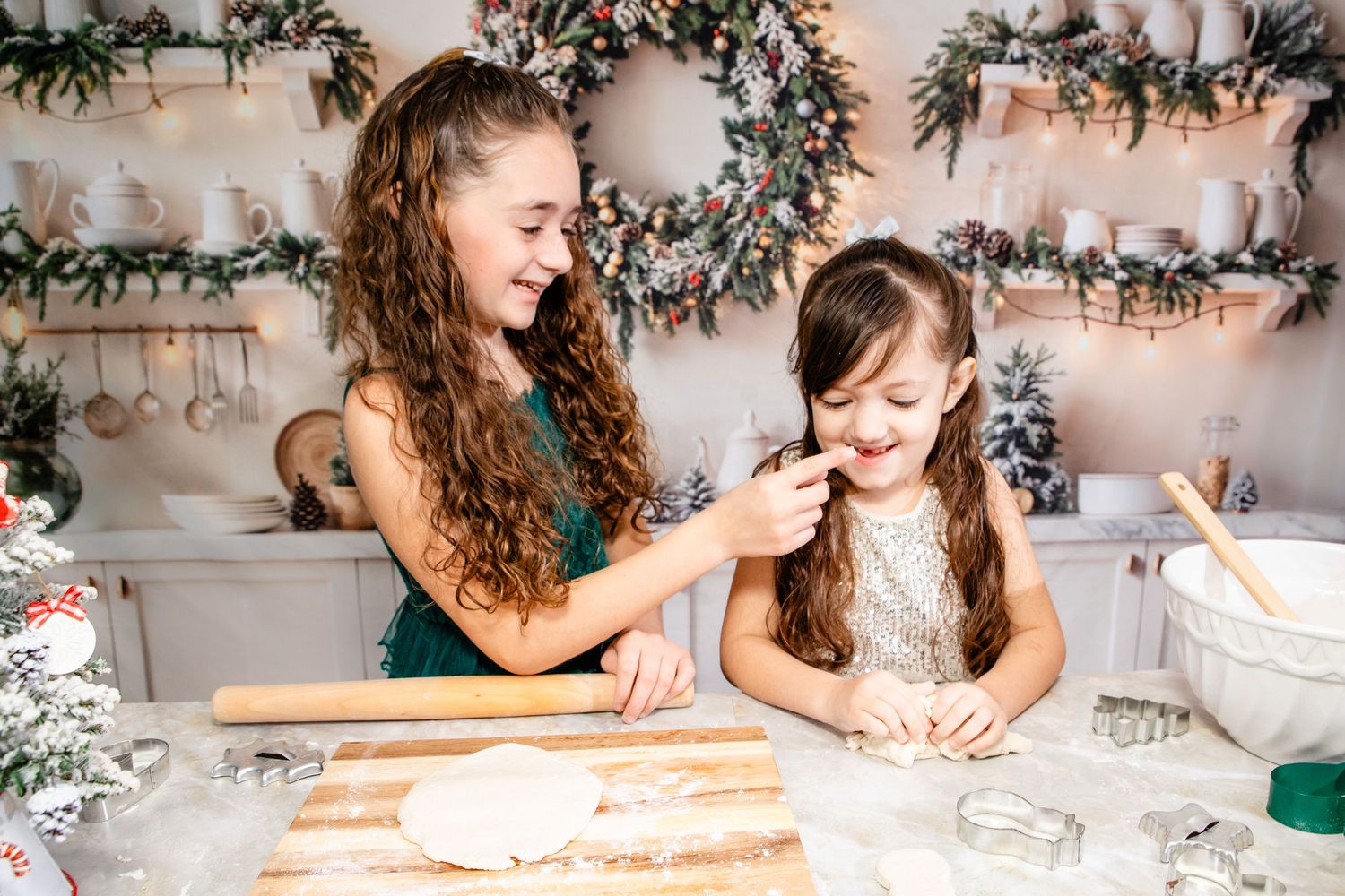 Rolling pin working dough on a rustic wooden surface with festive holiday decor and evergreen branches nearby.
