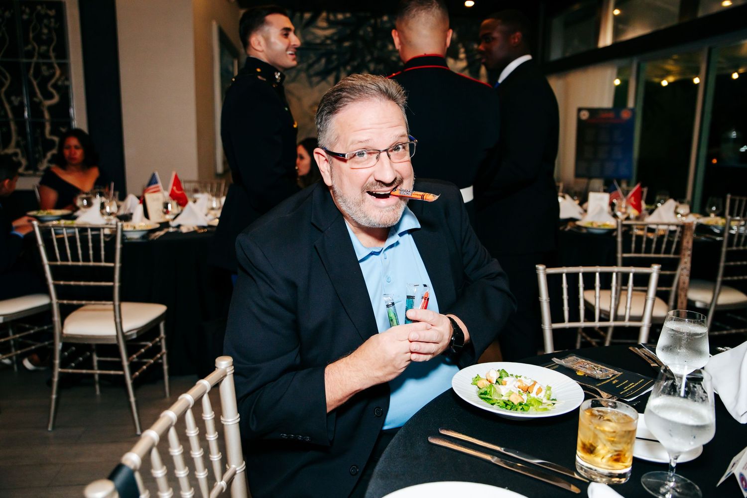 Guests enjoy dinner and drinks at formal tables during a military celebration.