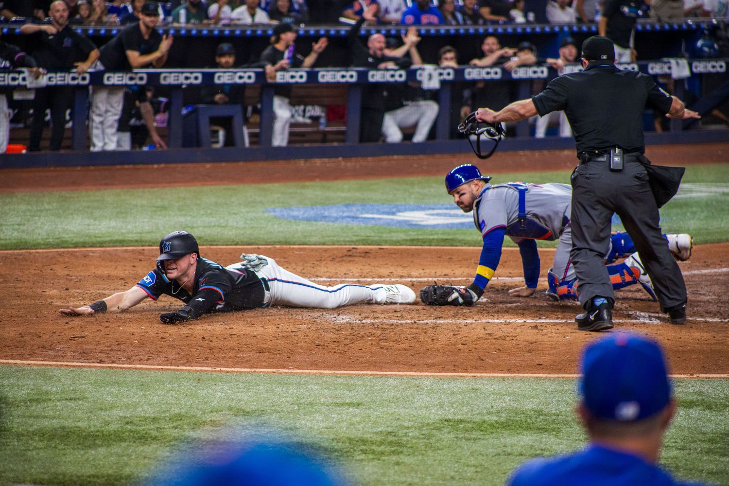 Baseball player makes diving slide into base as opponent attempts to make the tag.