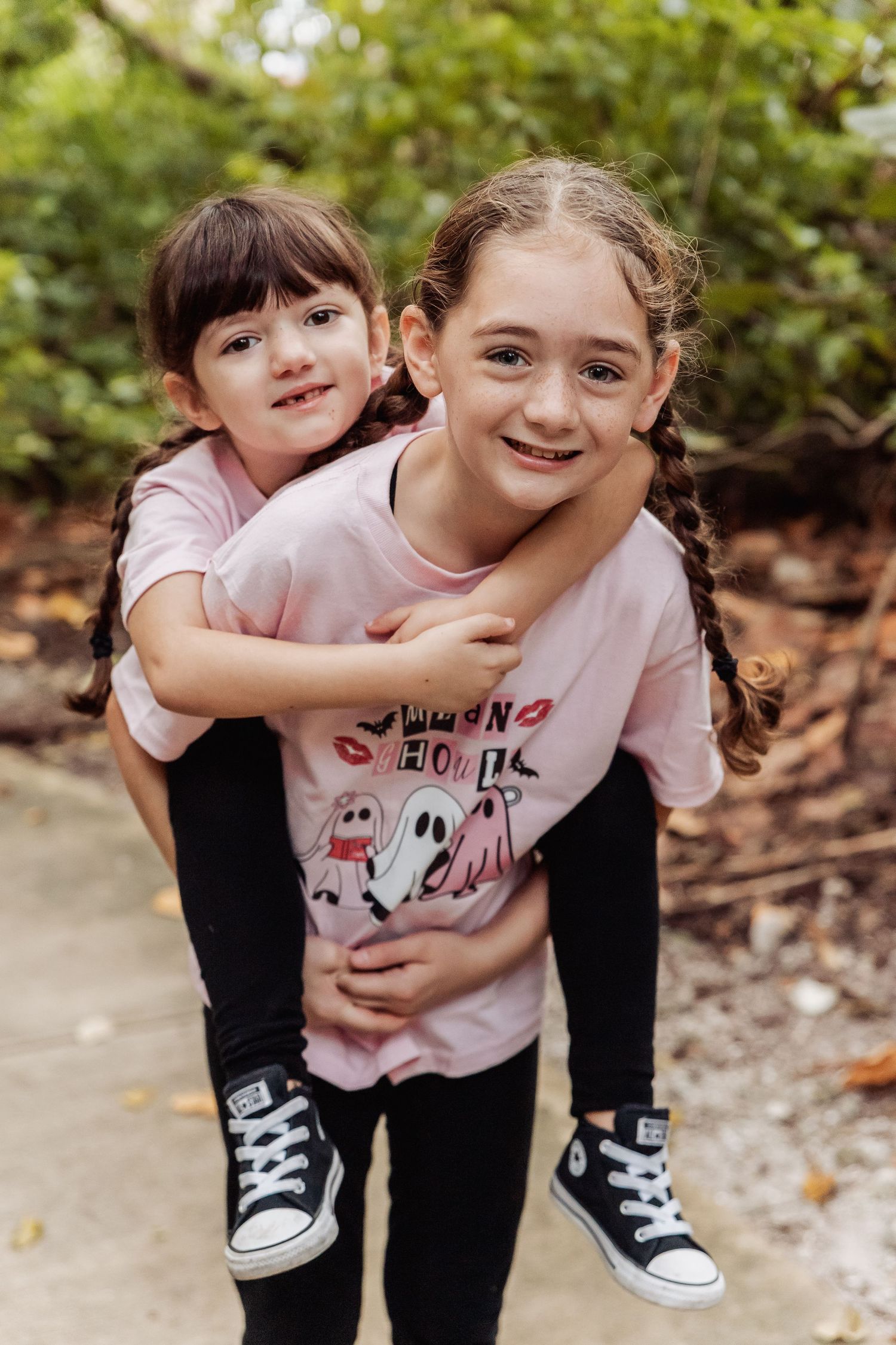A playful sequence of four photos showing two children hugging and laughing together outdoors while wearing matching shoes.