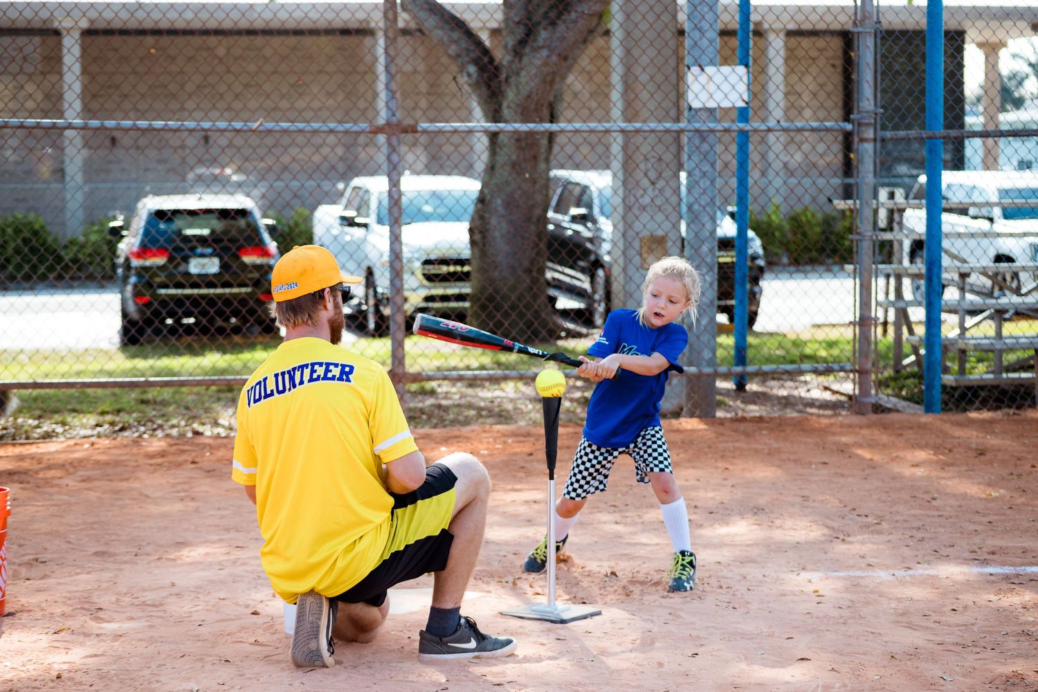 A baseball practice session on a dirt field with a player giving batting instructions on a sunny day.