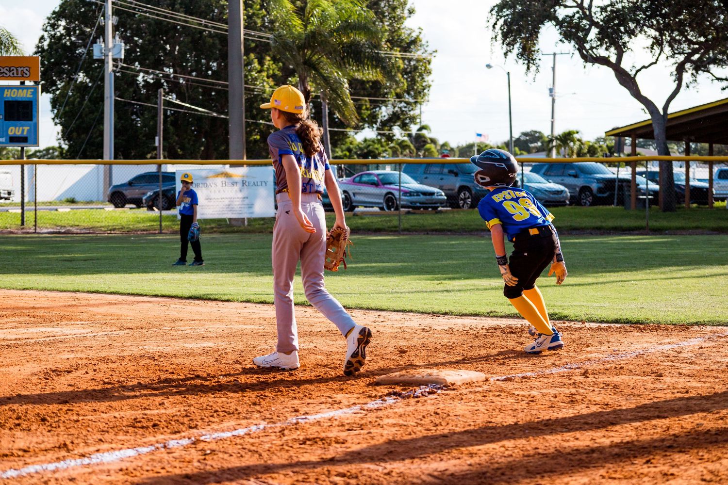 Youth baseball players compete at home plate during a little league game on a sunny afternoon at a local baseball field.